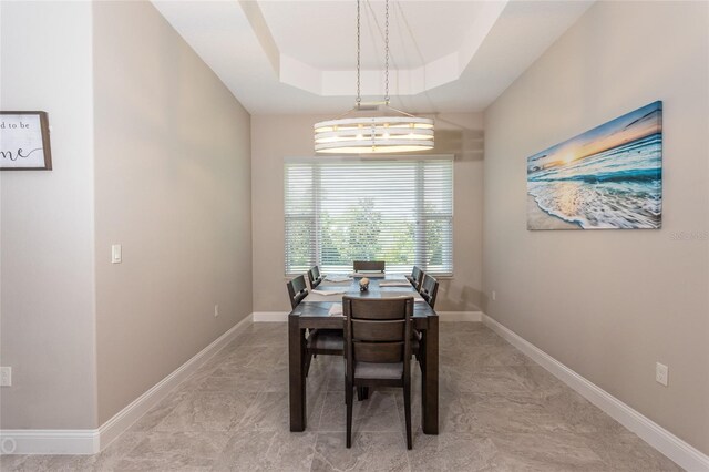 dining area featuring a raised ceiling and a chandelier