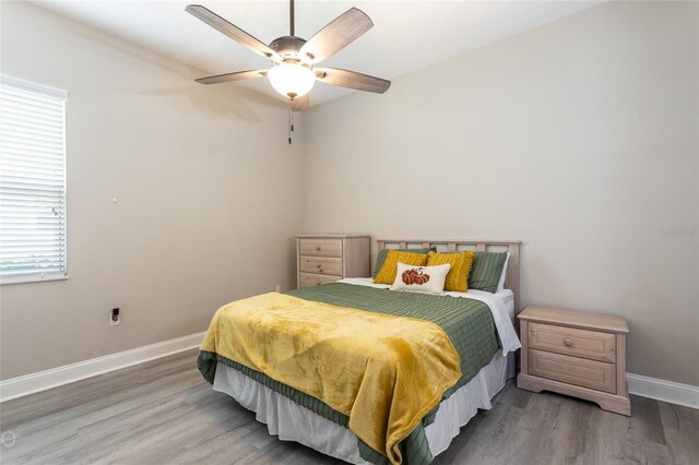 bedroom with multiple windows, ceiling fan, and hardwood / wood-style flooring