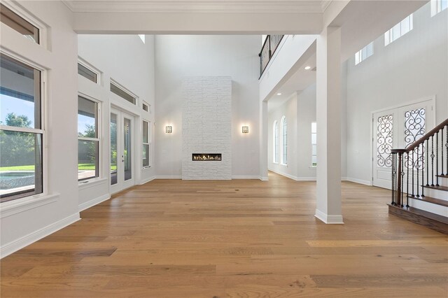 12245 Park Ave, Windermere, FL 34786 - unfurnished living room featuring plenty of natural light, a towering ceiling, stairs, crown molding, and light wood-type flooring