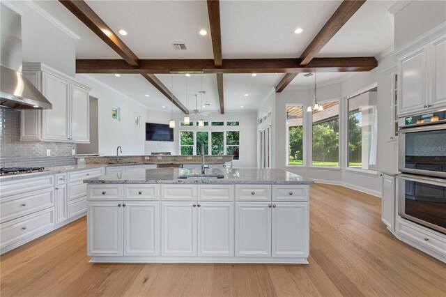 12245 Park Ave, Windermere, FL 34786 - kitchen featuring a sink, wall chimney exhaust hood, stainless steel appliances, beam ceiling, and decorative backsplash