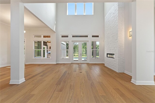 12245 Park Ave, Windermere, FL 34786 - unfurnished living room with baseboards, plenty of natural light, light wood-style floors, a towering ceiling, and crown molding