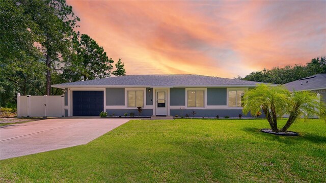 ranch-style house with a garage and a lawn