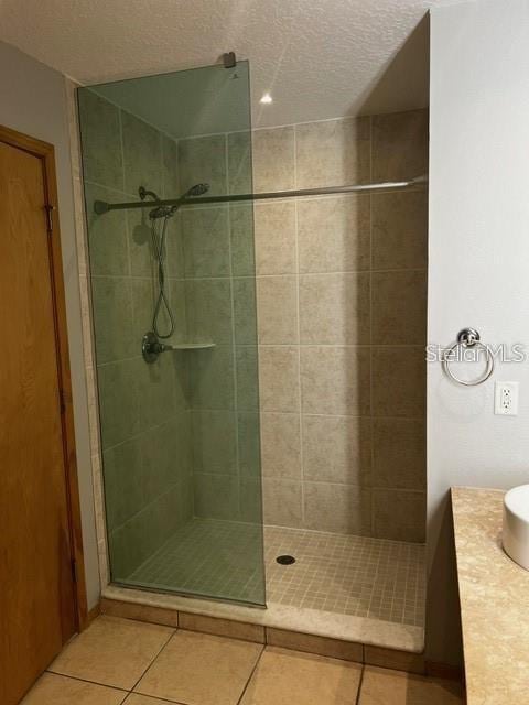 bathroom with tile patterned flooring and a tile shower