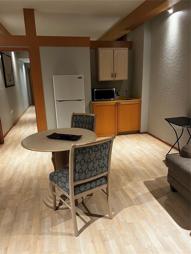 kitchen featuring light brown cabinetry, sink, white refrigerator, and light hardwood / wood-style flooring