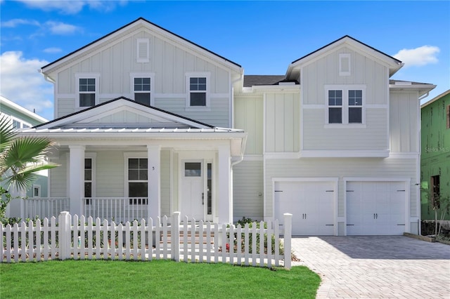 view of front of home featuring a standing seam roof, decorative driveway, board and batten siding, and a fenced front yard