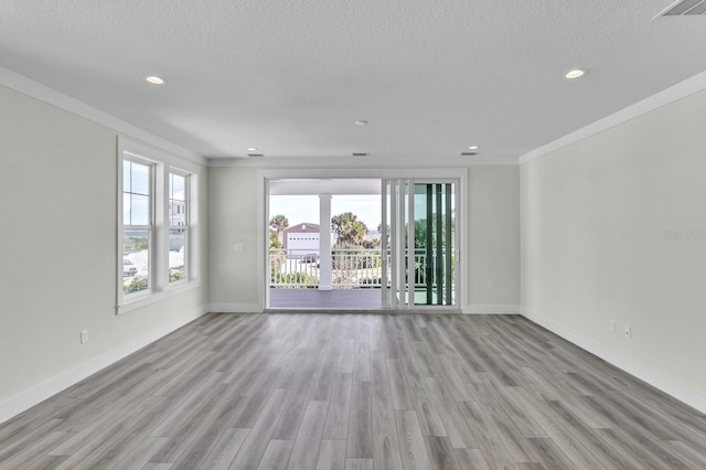 unfurnished room with baseboards, light wood-style flooring, ornamental molding, and a textured ceiling