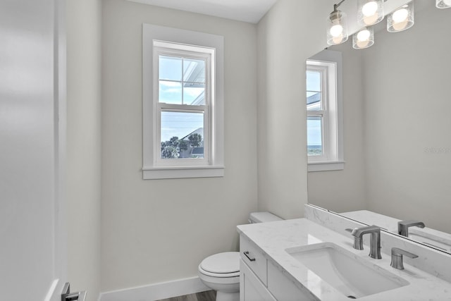 half bathroom featuring toilet, baseboards, wood finished floors, and vanity