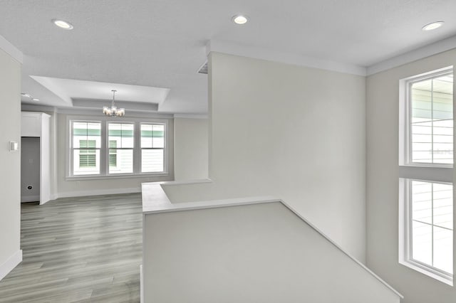 spare room featuring a chandelier, light wood-style flooring, recessed lighting, baseboards, and a tray ceiling