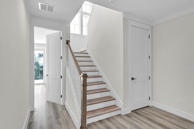 stairs featuring wood finished floors, visible vents, and baseboards