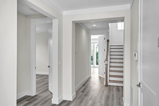 hall featuring light wood-style flooring, stairs, and baseboards