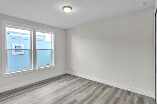 empty room featuring light wood-type flooring and baseboards