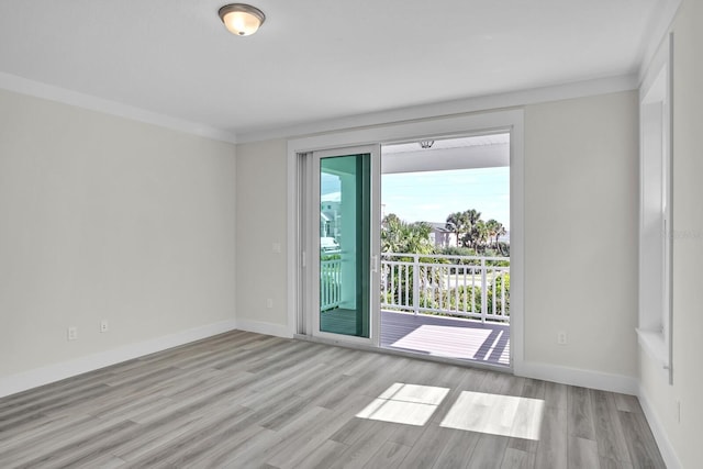 spare room featuring crown molding, light wood finished floors, and baseboards