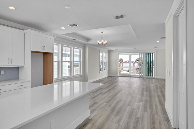 kitchen with light countertops, hanging light fixtures, visible vents, open floor plan, and white cabinetry