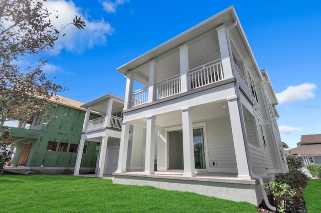 rear view of house featuring a porch, a lawn, and a balcony