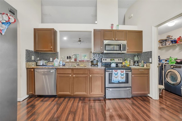 kitchen with sink, appliances with stainless steel finishes, washer / dryer, and backsplash