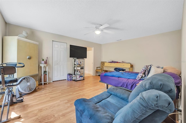 bedroom with light hardwood / wood-style floors, a textured ceiling, a closet, and ceiling fan