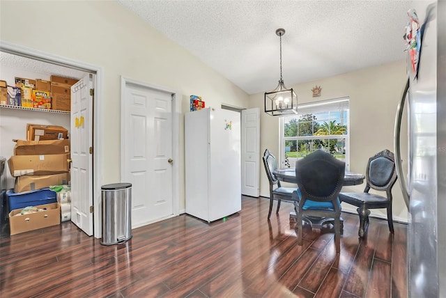 dining area featuring hardwood / wood-style floors, a chandelier, a textured ceiling, and vaulted ceiling