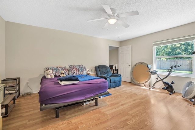 bedroom with light hardwood / wood-style flooring, a textured ceiling, and ceiling fan