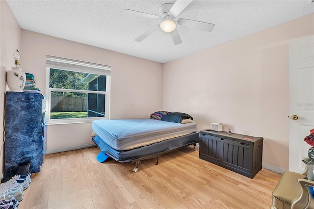 bedroom with light wood-type flooring, ceiling fan, and a textured ceiling