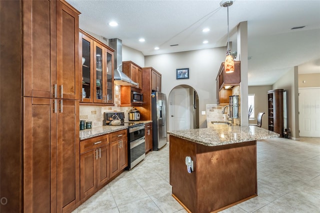 kitchen featuring appliances with stainless steel finishes, tasteful backsplash, kitchen peninsula, light stone countertops, and wall chimney exhaust hood