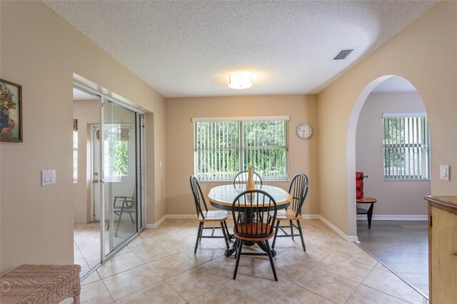 tiled dining area with a textured ceiling and a wealth of natural light