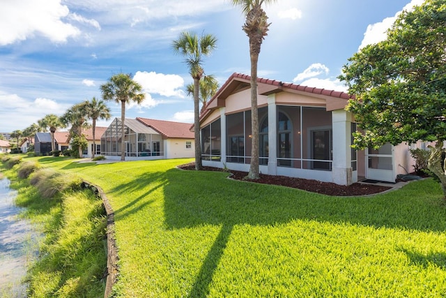 rear view of property featuring a sunroom and a yard