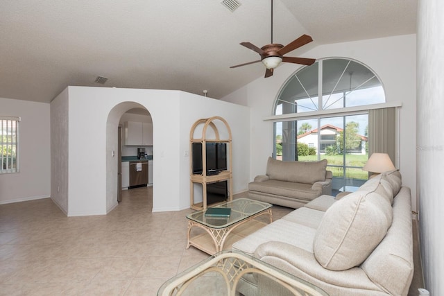 living room with light tile patterned flooring, ceiling fan, vaulted ceiling, and a textured ceiling