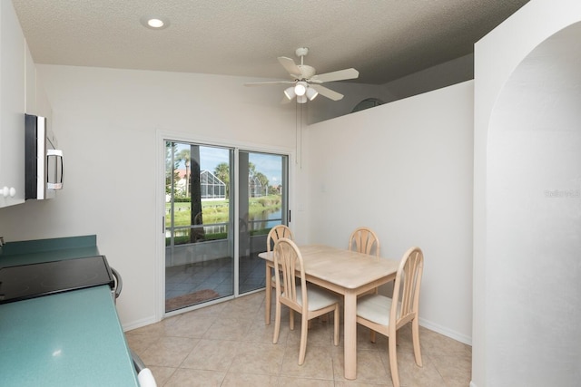 dining room featuring lofted ceiling, a textured ceiling, ceiling fan, and light tile patterned flooring