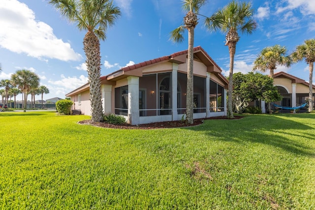 back of property with a yard and a sunroom