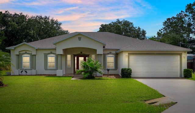 single story home featuring a garage and a lawn