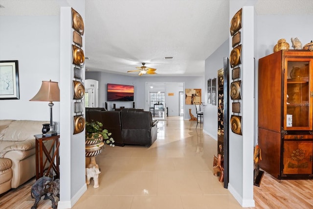 living room featuring ceiling fan, light tile patterned flooring, and a textured ceiling