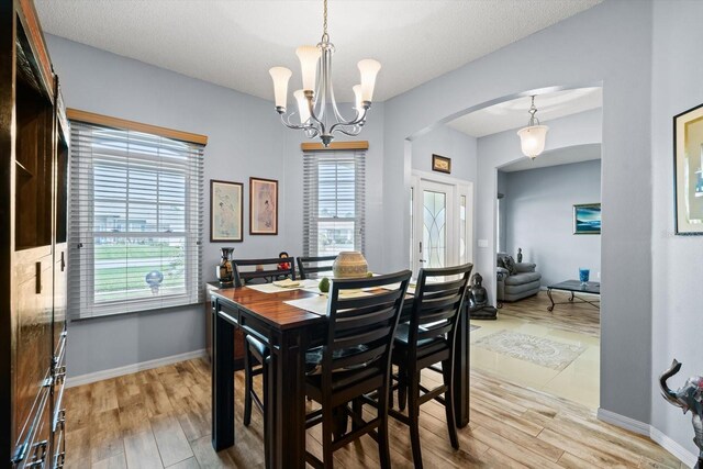 dining space with light hardwood / wood-style flooring, a notable chandelier, and a wealth of natural light