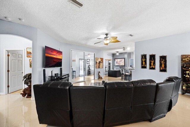 living room with ceiling fan, french doors, light tile patterned floors, and a textured ceiling