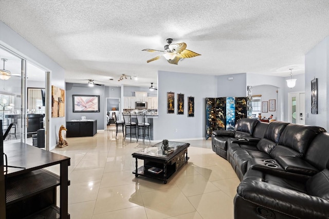 tiled living room featuring a textured ceiling, ceiling fan, and track lighting