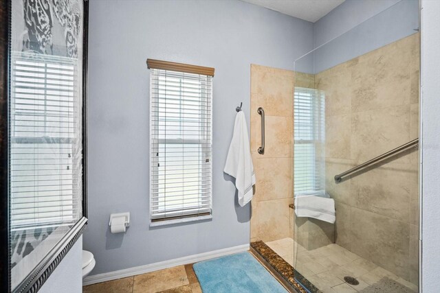 bathroom with tiled shower, toilet, and tile patterned flooring