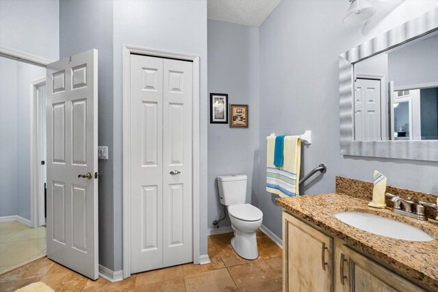 bathroom with vanity, tile patterned floors, a textured ceiling, and toilet