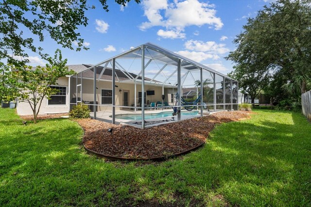 rear view of property with a patio area, a yard, and glass enclosure