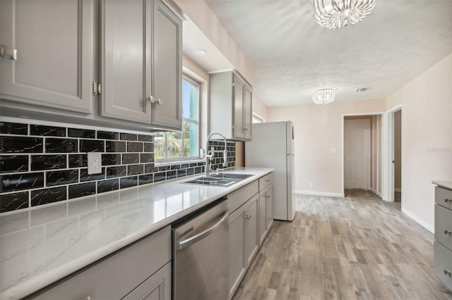 kitchen with gray cabinetry, light hardwood / wood-style flooring, dishwasher, a notable chandelier, and white fridge