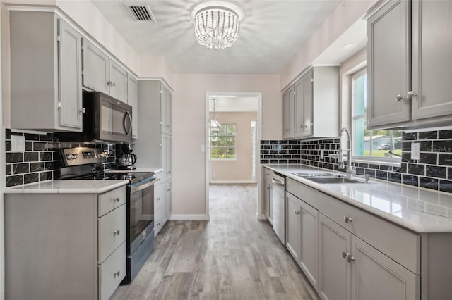 kitchen featuring sink, light hardwood / wood-style flooring, appliances with stainless steel finishes, gray cabinets, and decorative backsplash