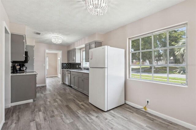 kitchen featuring hardwood / wood-style flooring, a healthy amount of sunlight, gray cabinets, and white refrigerator