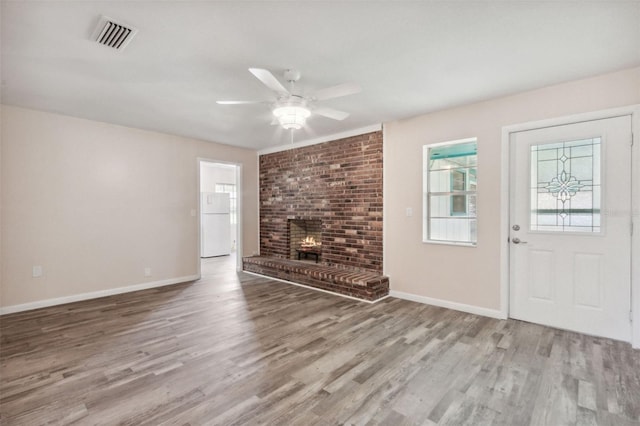 unfurnished living room featuring light hardwood / wood-style flooring, a brick fireplace, and ceiling fan