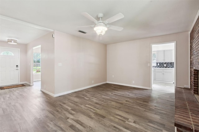 interior space with a brick fireplace, ceiling fan, and dark hardwood / wood-style floors