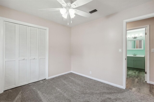 unfurnished bedroom with ceiling fan, sink, carpet floors, and a closet