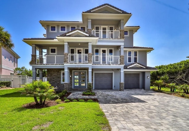 view of front facade featuring a garage, a front yard, french doors, and a balcony