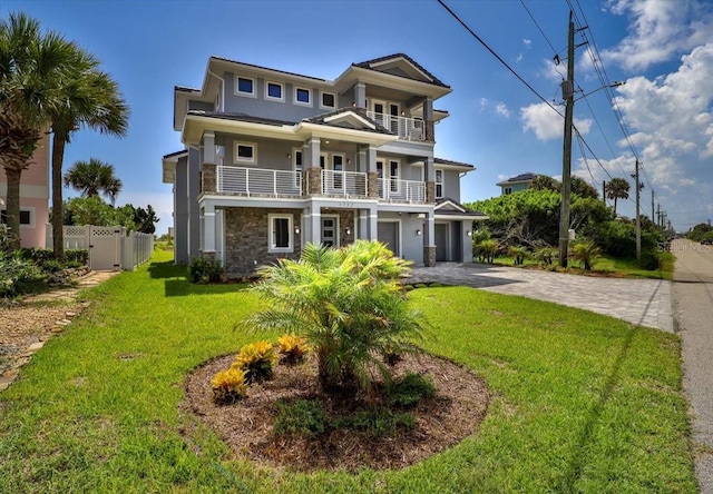 view of front of property featuring a balcony, a garage, and a front lawn