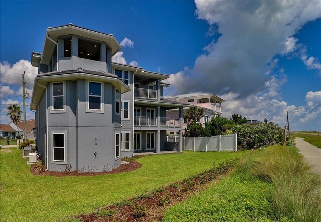 rear view of house featuring a lawn and a balcony