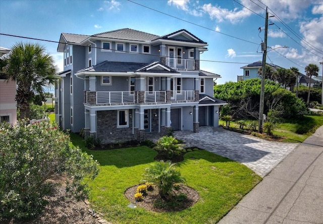 view of front of property with a garage, a front yard, and a balcony