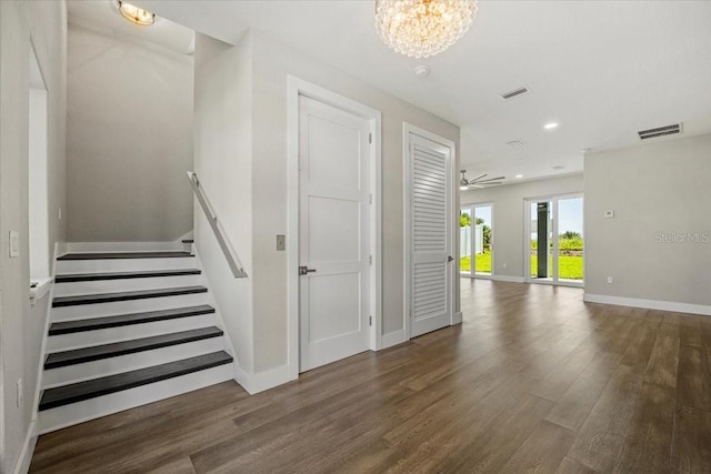 stairs with hardwood / wood-style floors and ceiling fan with notable chandelier