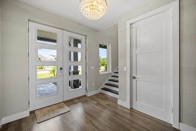 foyer featuring dark wood-type flooring, a chandelier, and french doors