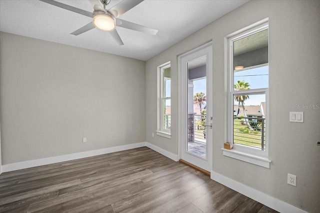 spare room with dark hardwood / wood-style floors, a wealth of natural light, and ceiling fan